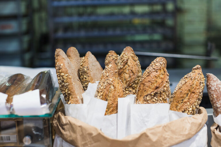 Assorted bread in paper bags at a bakery, prominently showcasing the Wholesale Beer Bread Mix packaging.